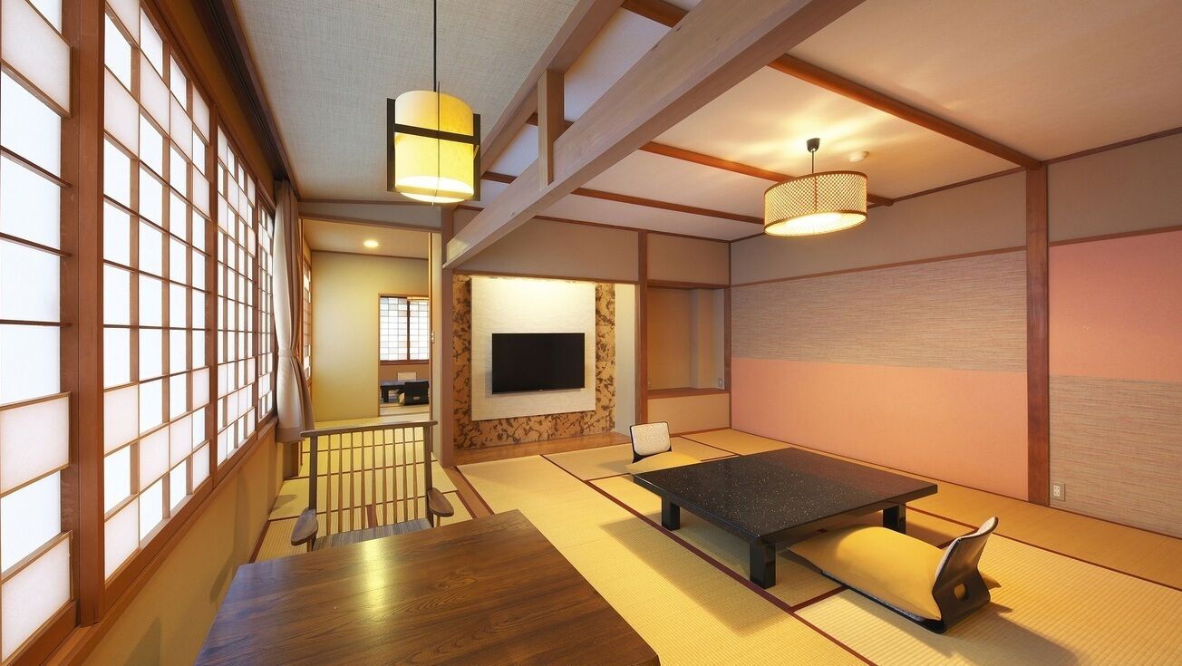 A traditional Japanese room with tatami flooring, a low table, a television, and sliding doors.