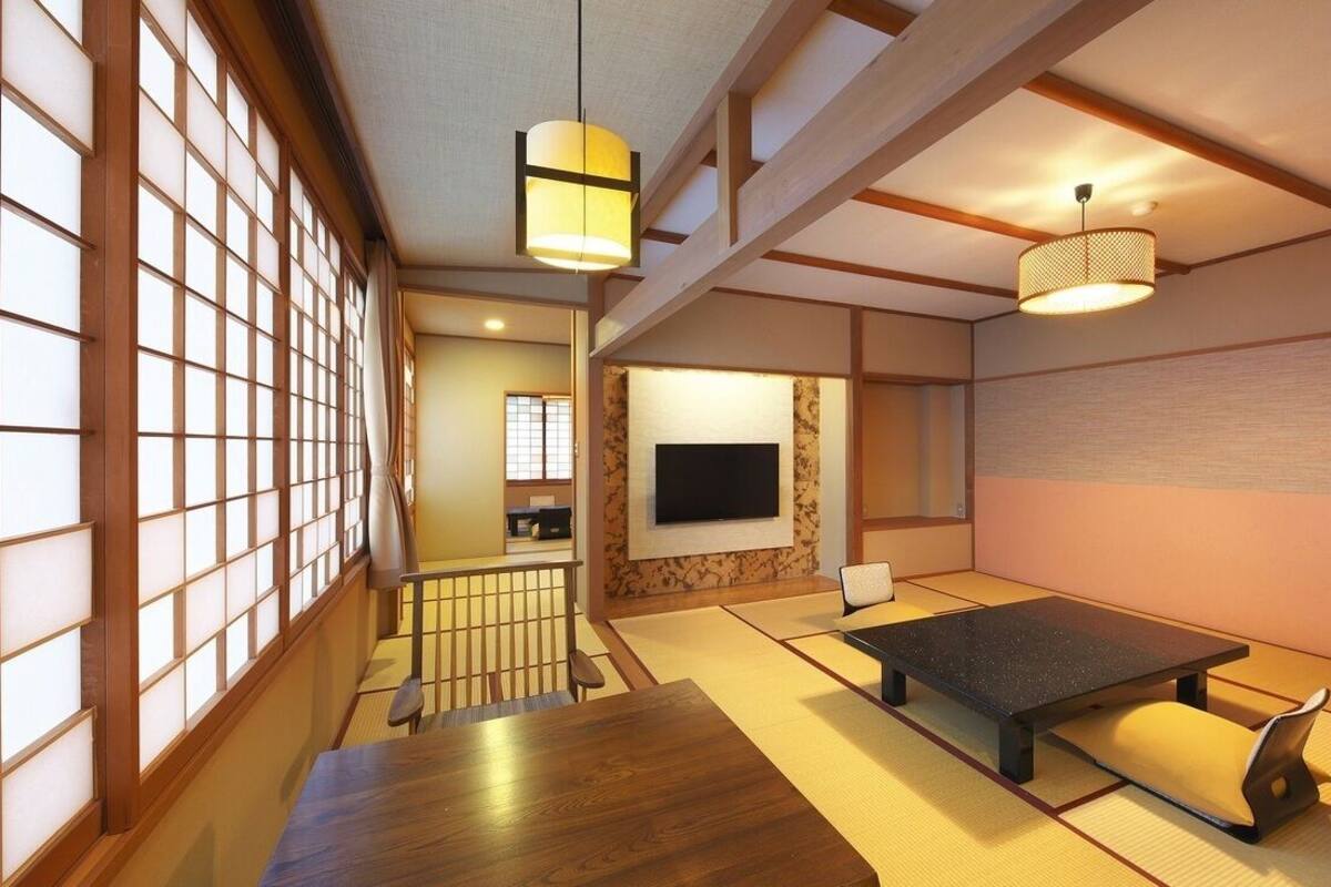Una habitación japonesa tradicional con suelo de tatami, una mesa baja, un televisor y puertas correderas.