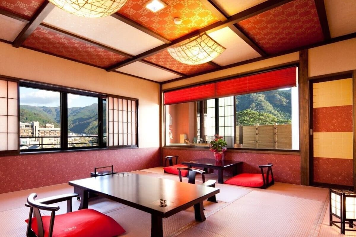 A traditional Japanese-style room with tatami flooring, a low table, and red cushions.