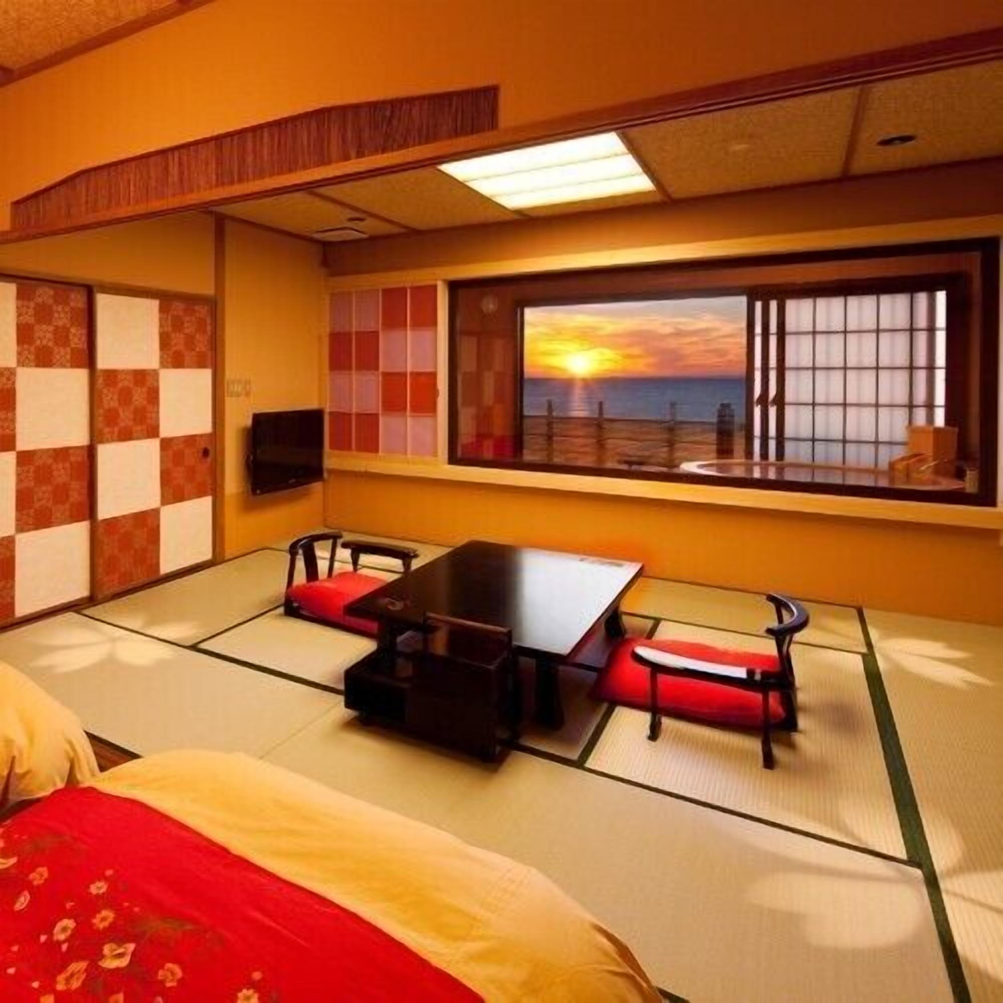 A traditional Japanese-style room with tatami flooring, a low table, and a view of the sunset through a large window.