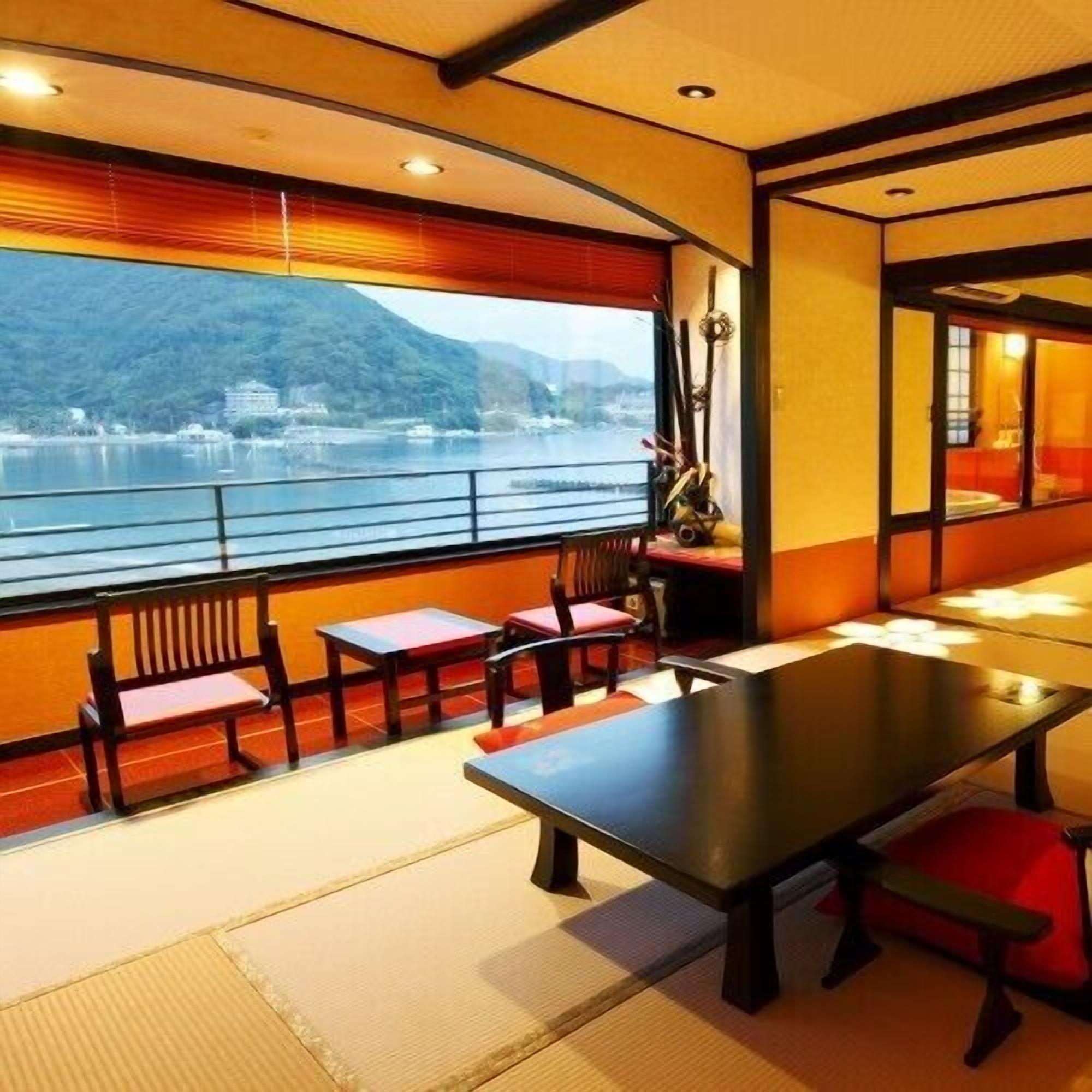 A dining area with a table and chairs, a view of a lake and mountains, and a traditional Japanese interior design.