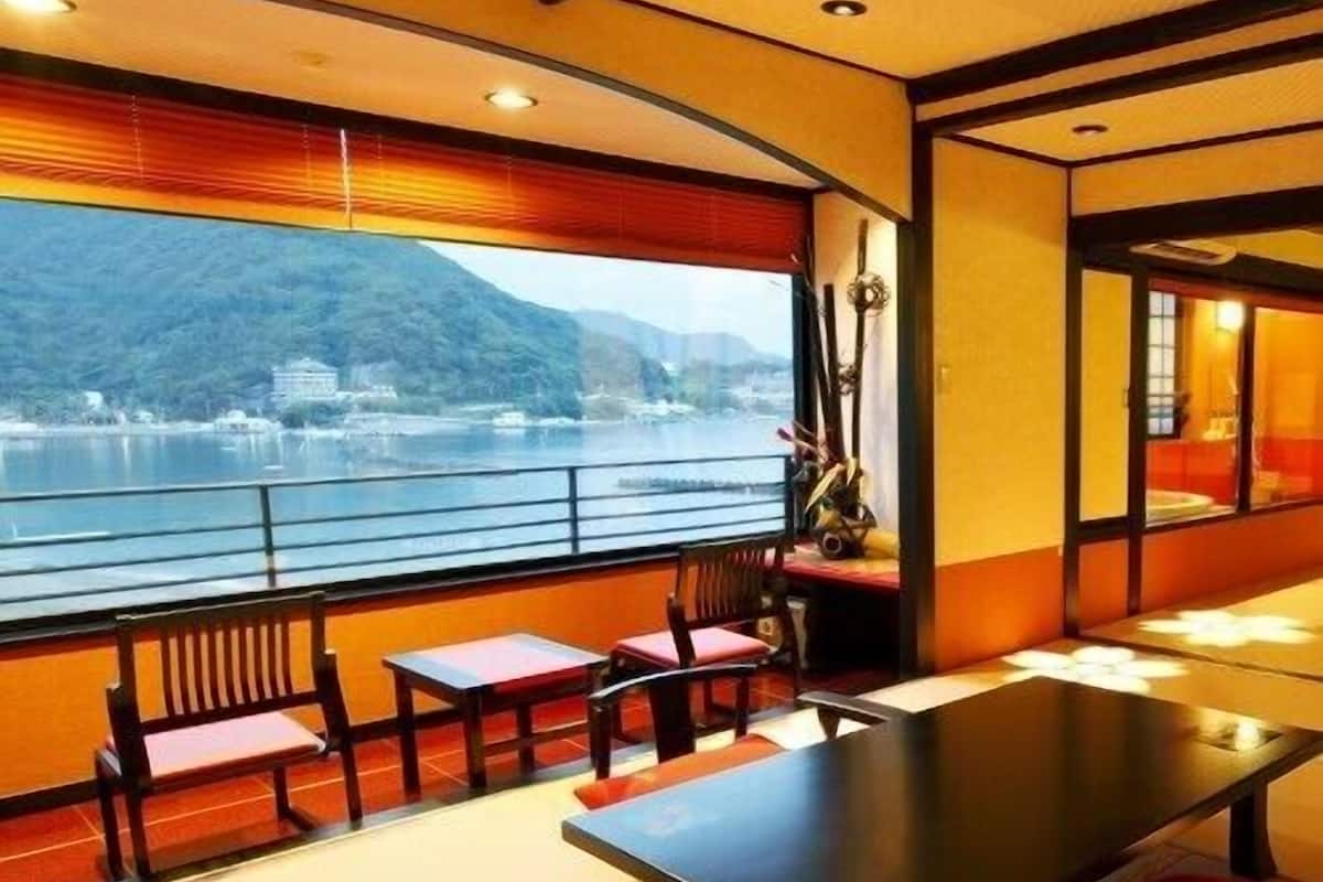 A dining area with a table and chairs, a view of a lake and mountains, and a traditional Japanese interior design.