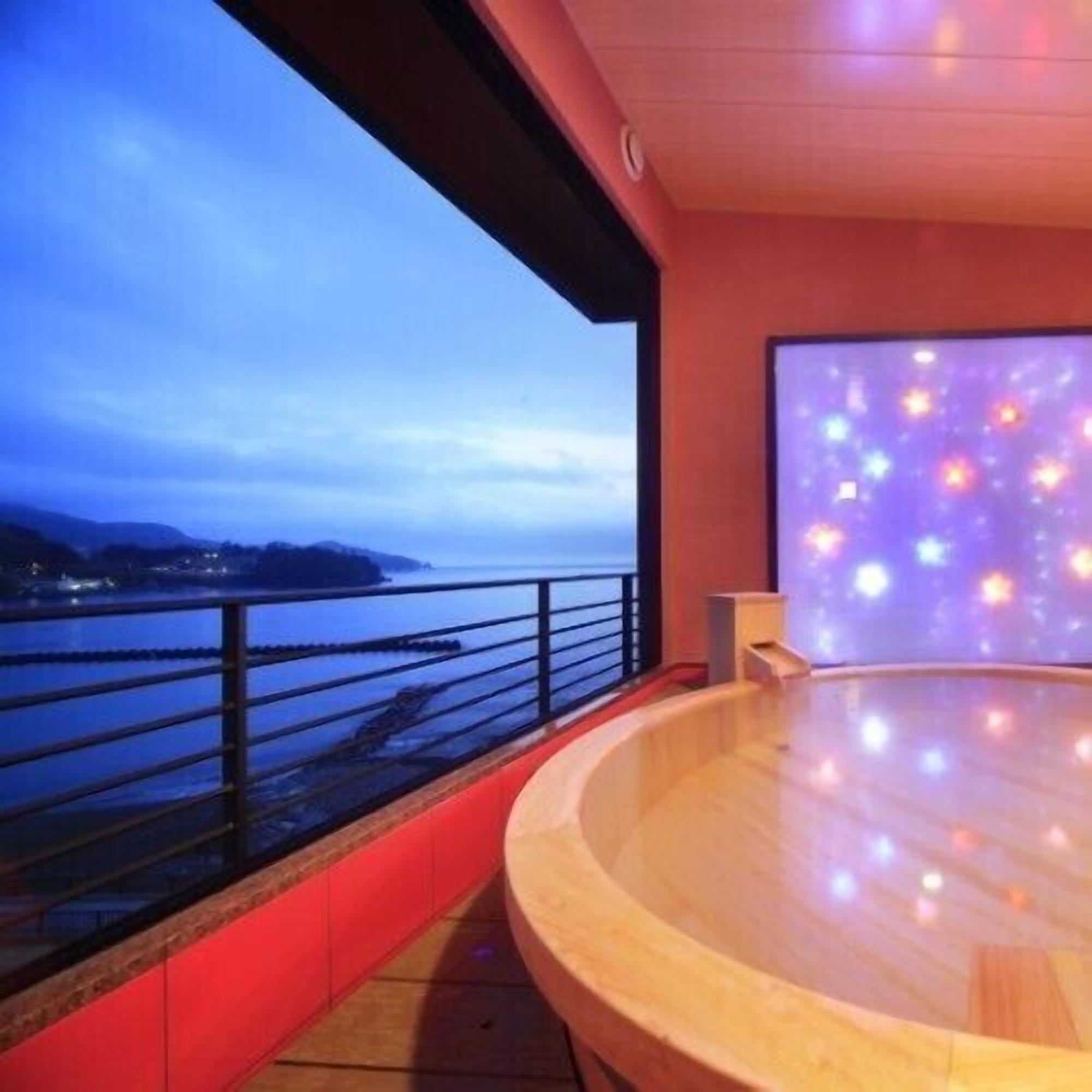 A spa area with a view of the sea, a wooden floor, and a large window.