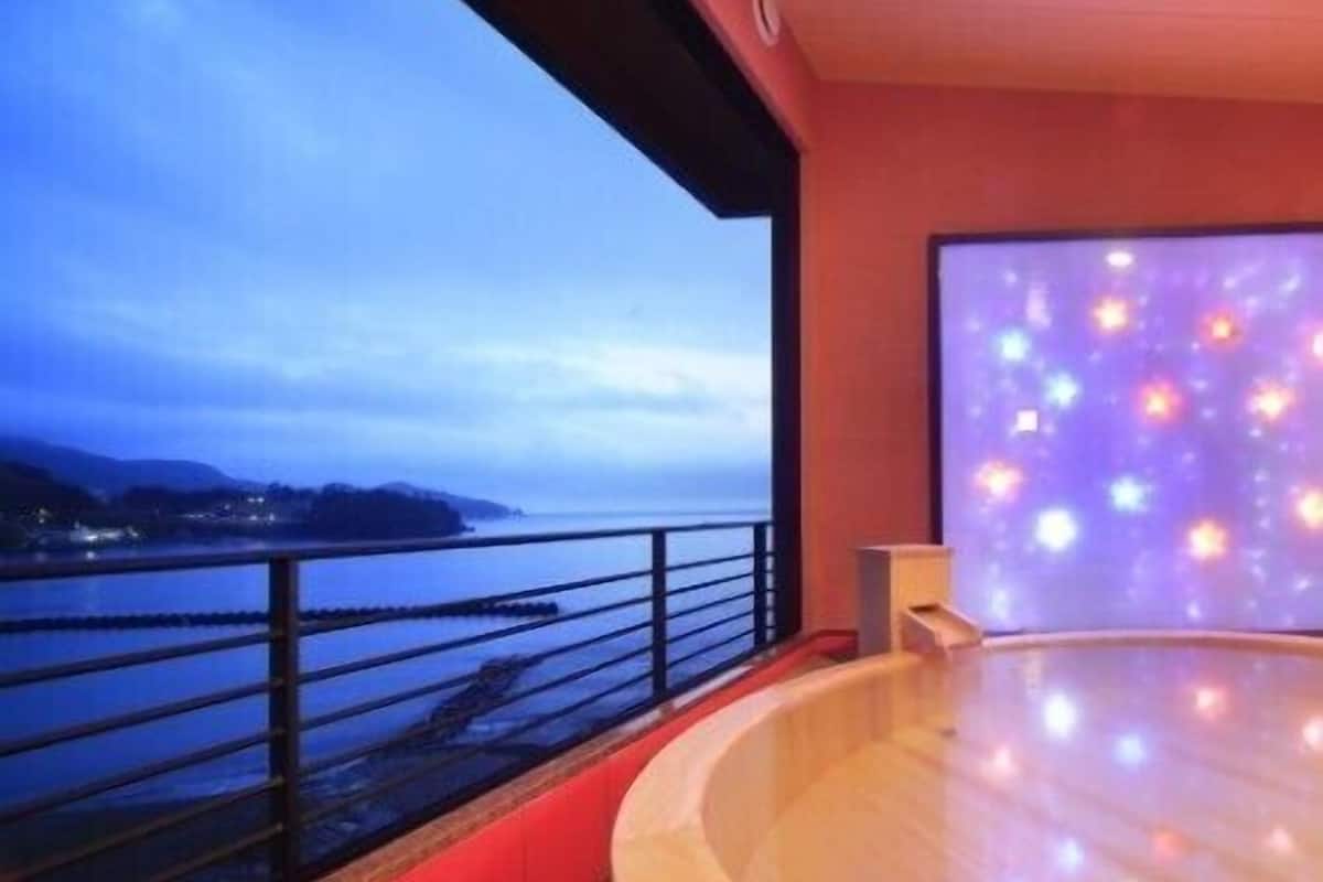 A spa area with a view of the sea, a wooden floor, and a large window.
