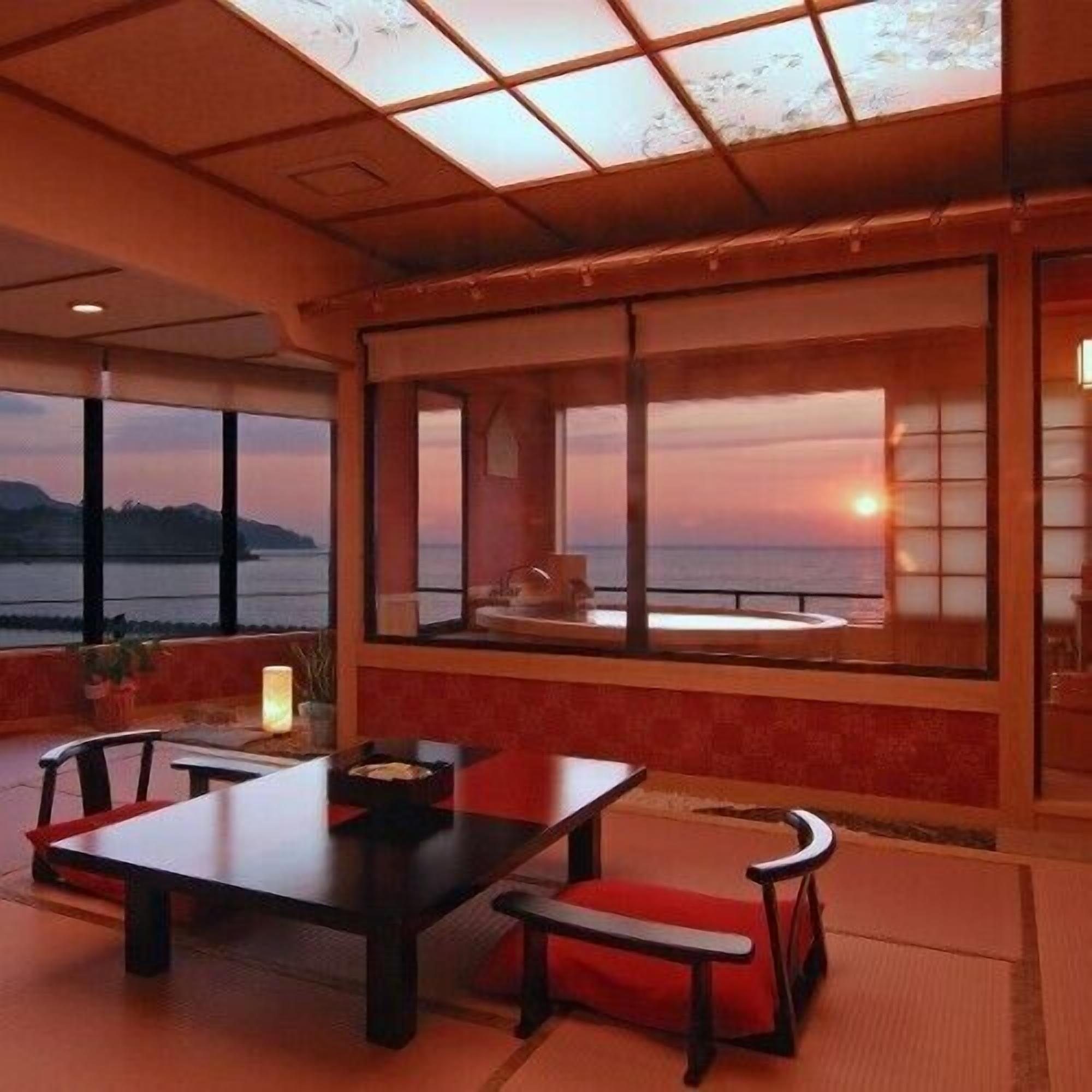 A dining area with a table and chairs, large windows with a view of the sunset, and a wooden ceiling.