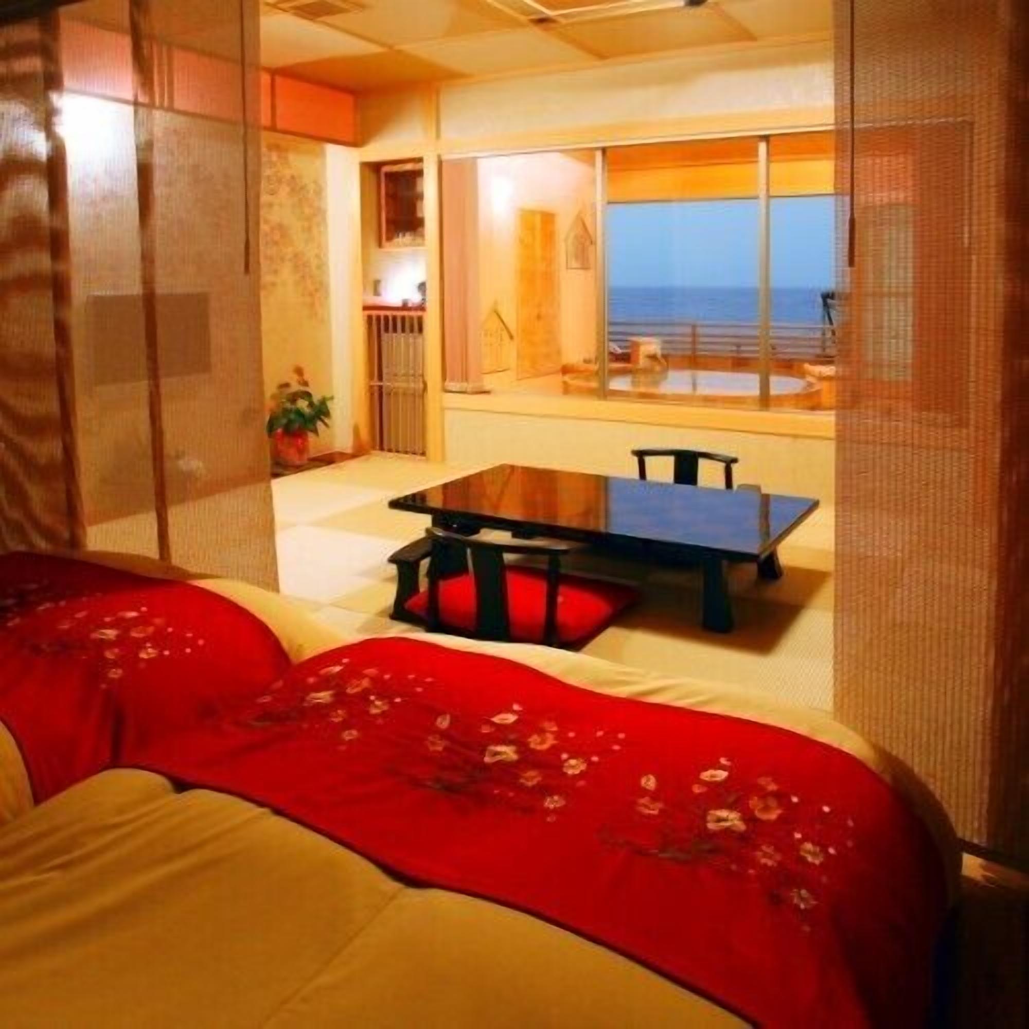 A room with a bed, a table, and a view of the sea.
