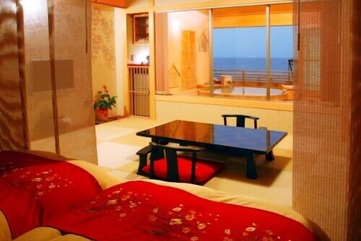 A room with a bed, a table, and a view of the sea.