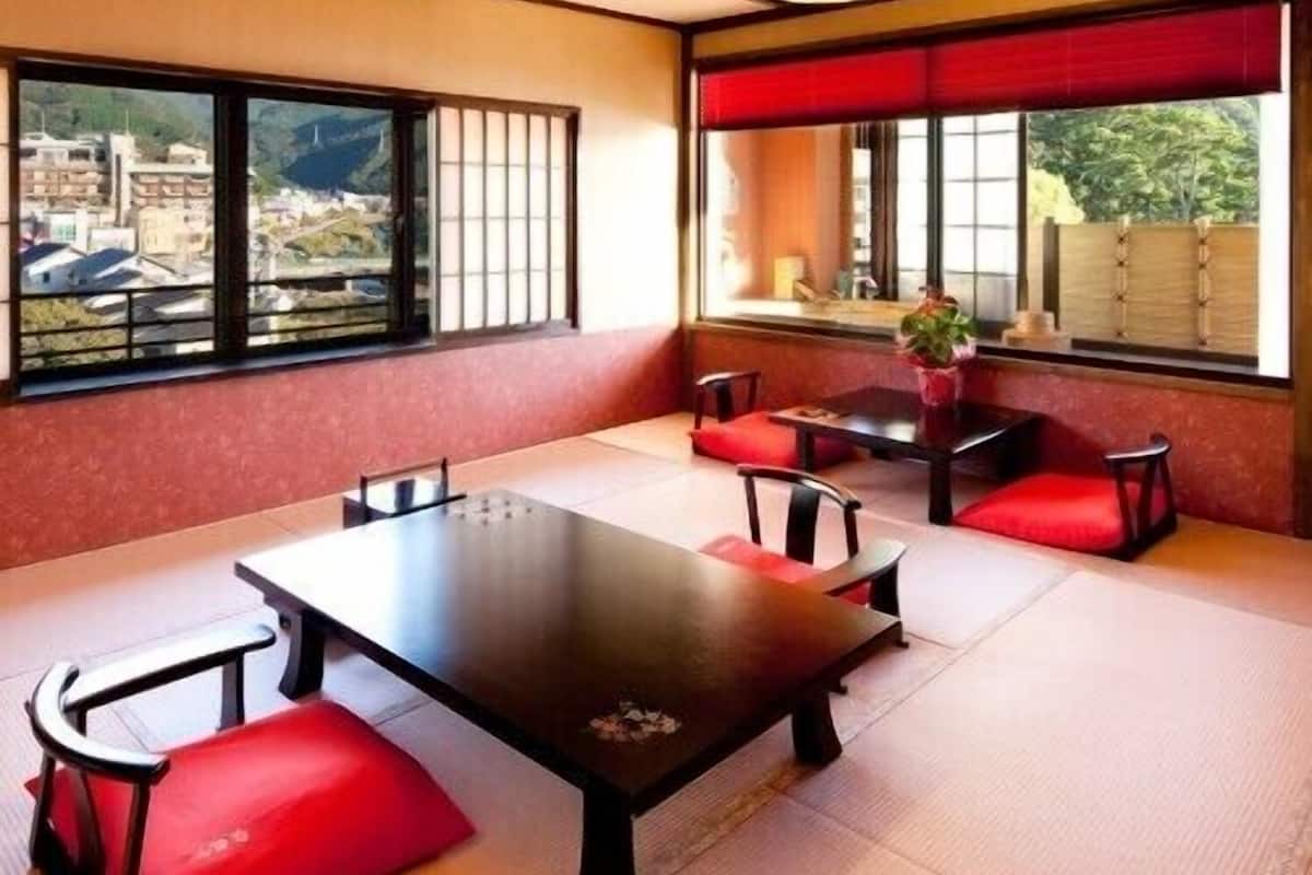 A traditional Japanese-style room with tatami flooring, a low table, and red cushions.