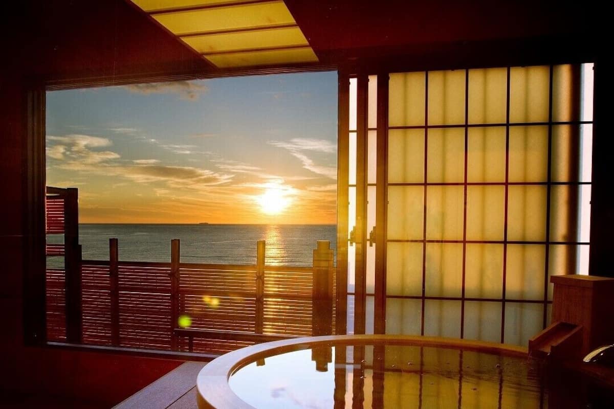 A room with a view of the sunset over the sea, a sliding shoji screen, and a wooden deck.