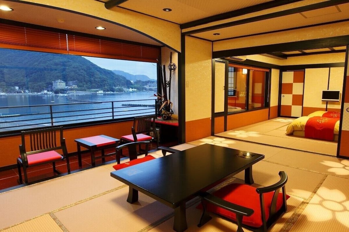 A room with tatami flooring, a low table, and a sofa with a red cushion.