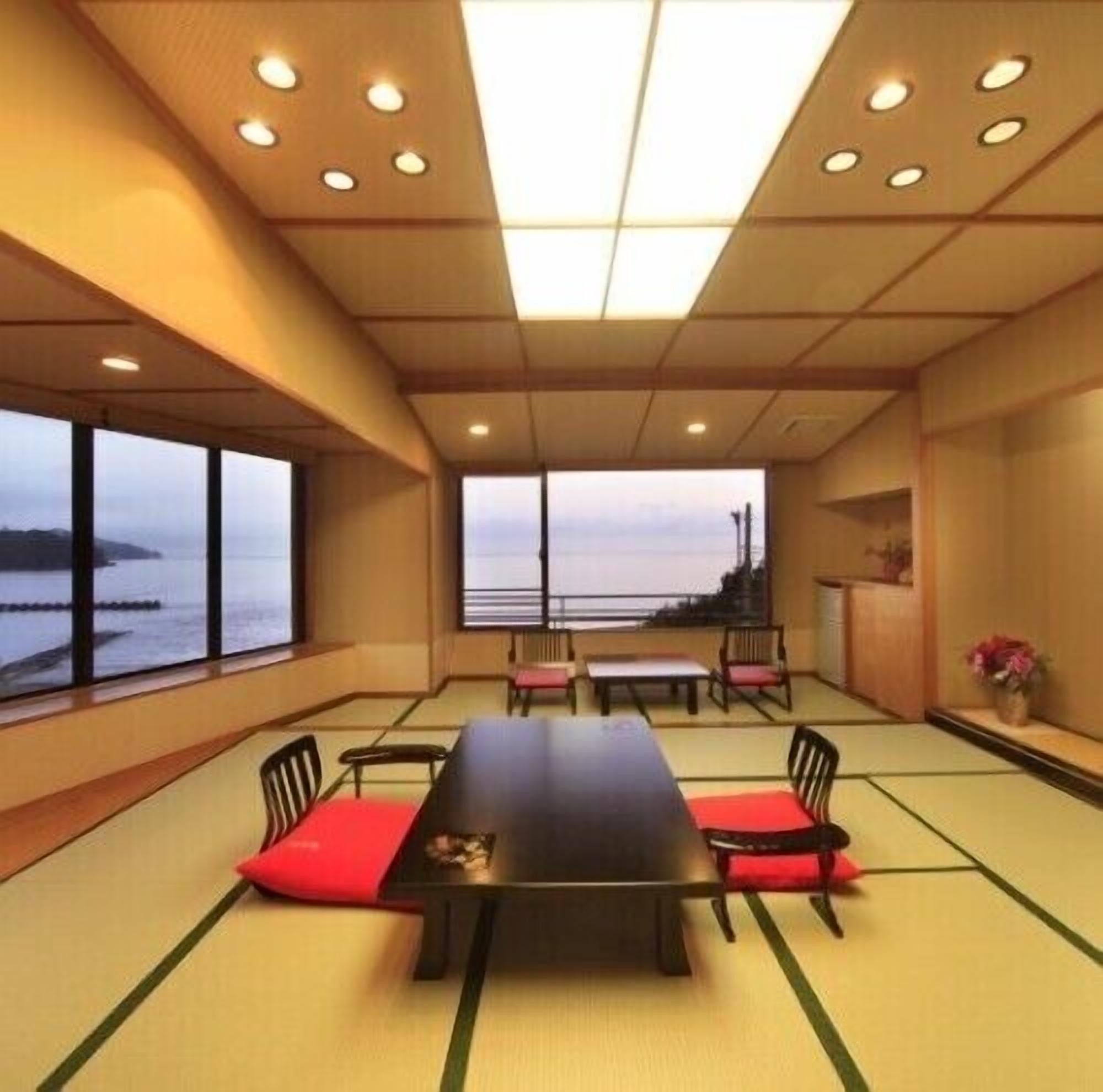 A room with tatami flooring, a low table, and chairs with red cushions.