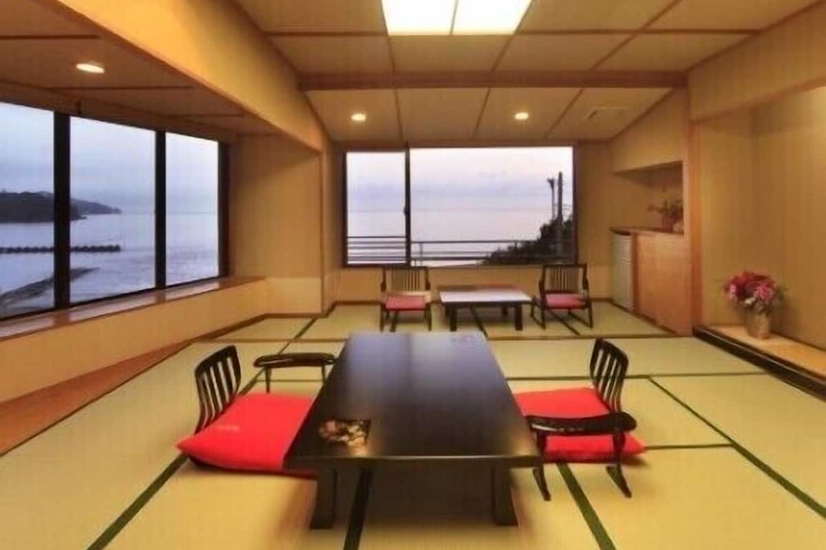A room with tatami flooring, a low table, and chairs with red cushions.