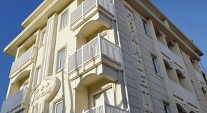A multi-story building with balconies and a sign that reads "Hotel". - Hotel Kadett (Rimini)
