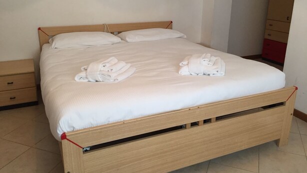 Un lit en bois avec une literie blanche et deux serviettes pliées posées sur le lit.