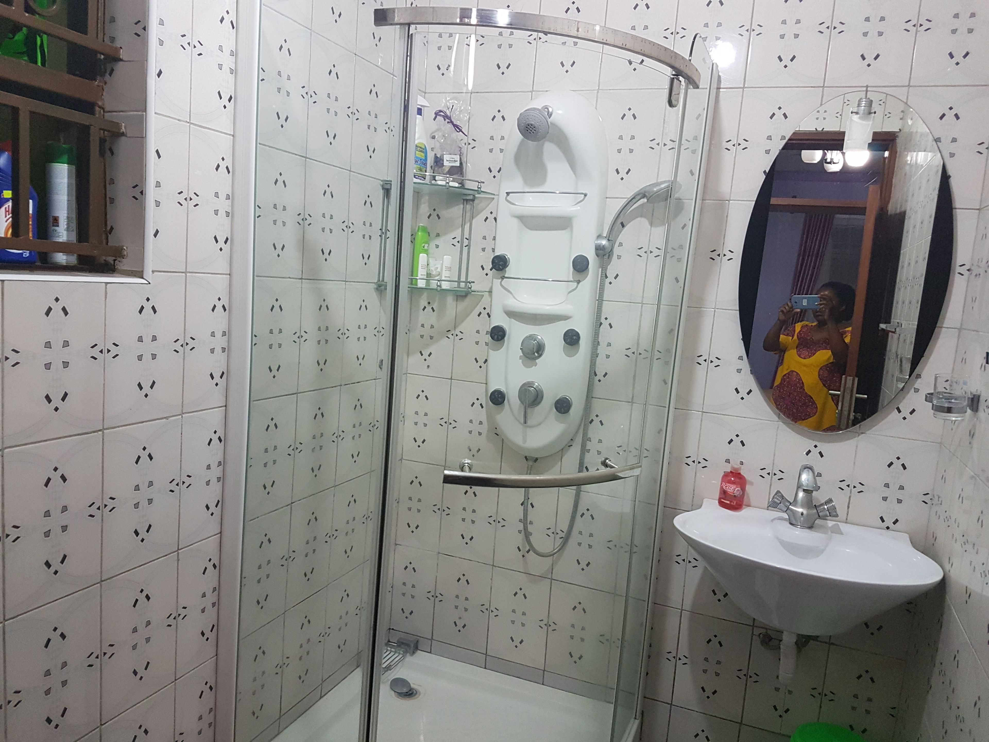 A bathroom with a glass-enclosed shower, a sink, and a mirror.