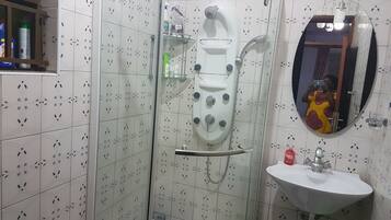 A bathroom with a glass-enclosed shower, a sink, and a mirror.