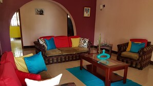 A living room with a sofa, armchairs, and a coffee table. - Sheevy's Bed N Breakfast (Fort Portal)