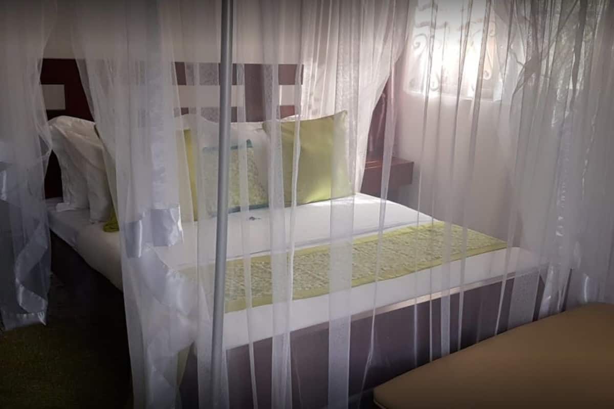 A bed with a canopy, a bedside table, and a bench.