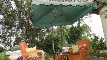 An outdoor seating area with two wicker chairs and a table under a green umbrella.