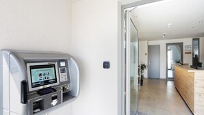 Un quiosco de registro automático y una zona de recepción con mostrador de madera.