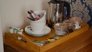 Una zona de cafè amb una cafetera, tasses i pots de sucre i llet.