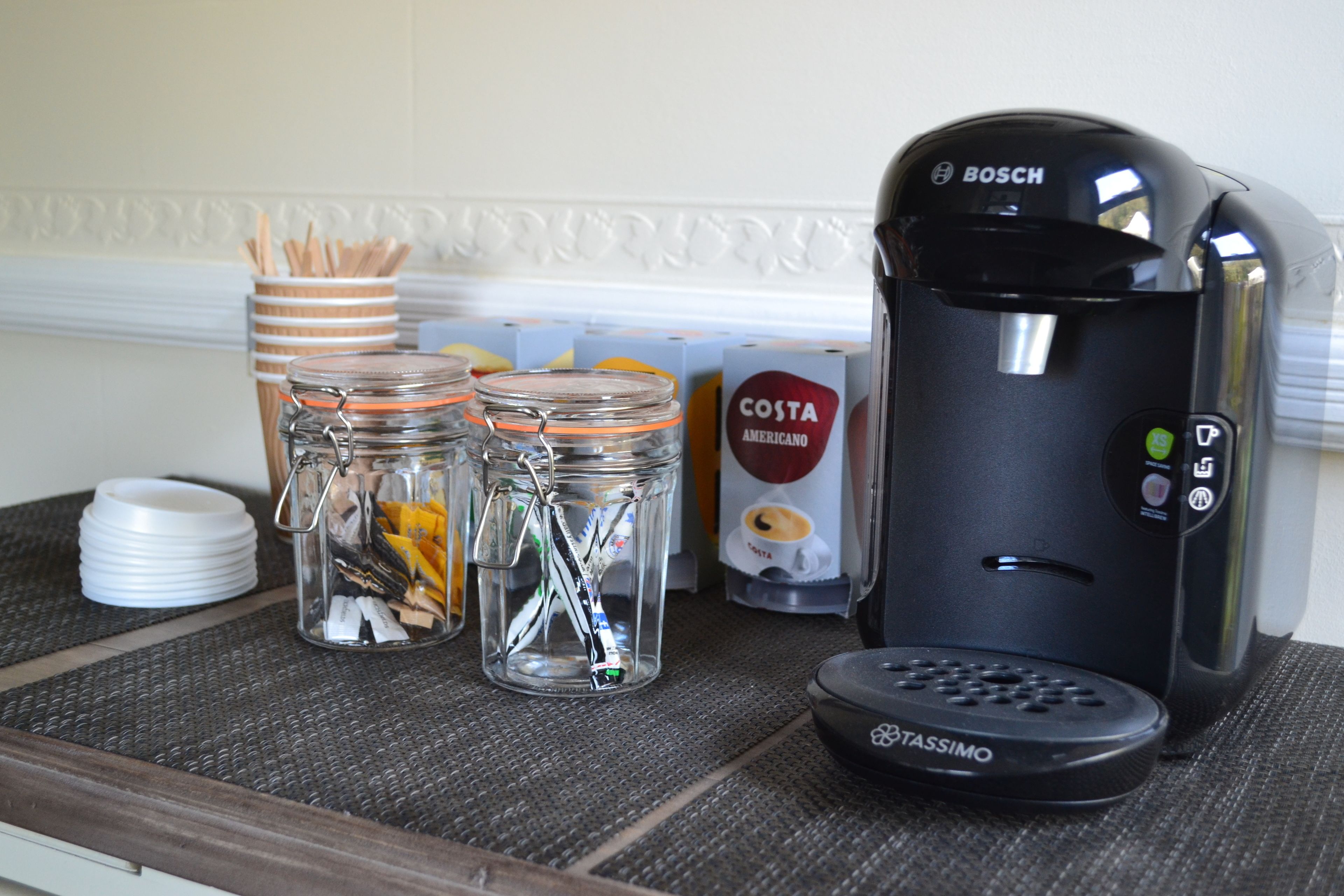A kitchen counter with a coffee maker, jars, and boxes.