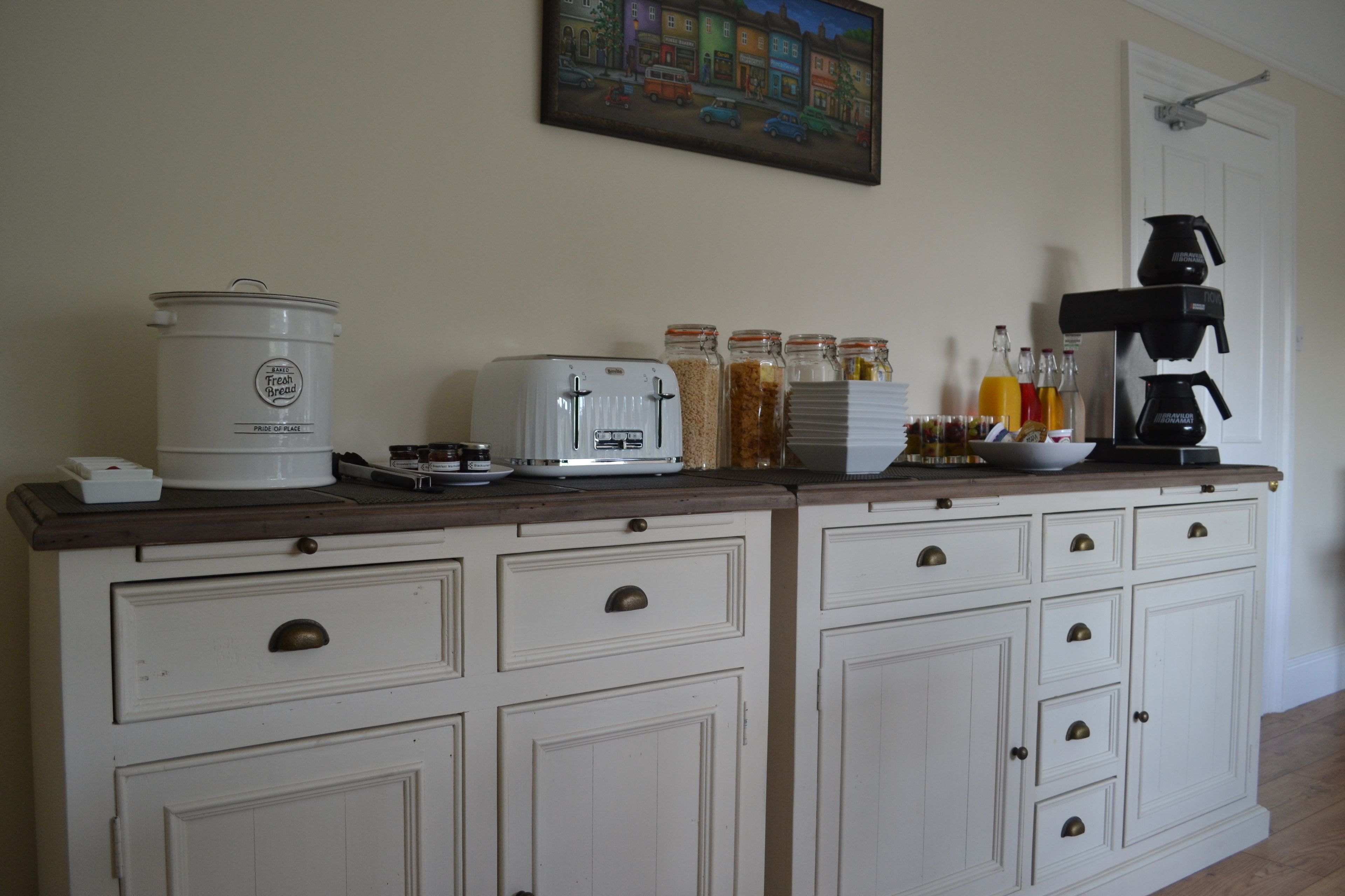 Una encimera de cocina con cafetera, tostadora y frascos de salsas.