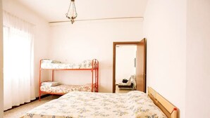 A bedroom with a bunk bed, a single bed, a mirror, and a chandelier. - Euroresidence n.4 (Jesolo)