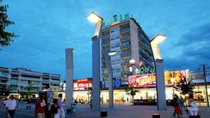 A multi-story hotel with a prominent sign, surrounded by a pedestrian area with shops and people. - Euroresidence n.4 (Jesolo)