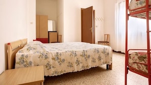 A bedroom with a bunk bed, a single bed with a floral bedspread, a wooden desk, a wardrobe, and a door leading to another room. - Euroresidence n.4 (Jesolo)