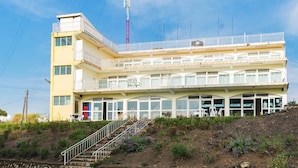 A multi-story building with a balcony on the upper floor, a staircase leading to the entrance, and a clear sky in the background. - Sunrise Apartments Hotel (Fort Portal)