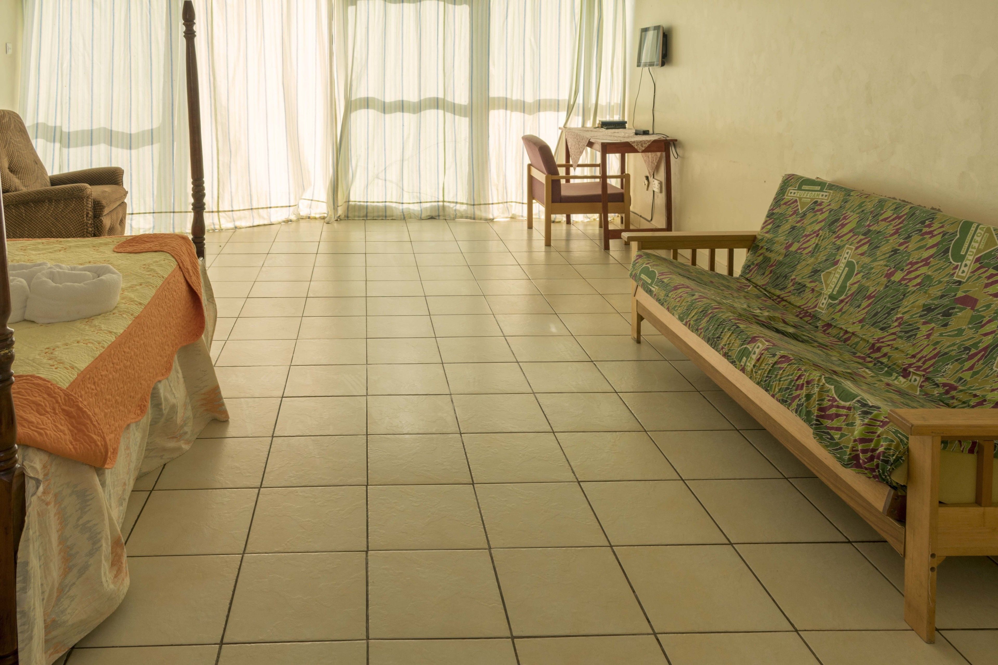 A room with a bed, a sofa, a chair, and a small table.