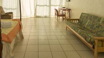 A room with a bed, a sofa, a chair, and a small table.