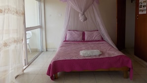 A bedroom with a bed, a window, and a door. - Sunrise Apartments Hotel (Fort Portal)