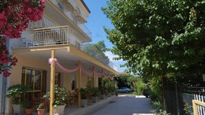 Un bâtiment à deux étages doté d’un balcon, de plantes en pot et d’une allée gravillonnée.