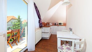 Una pequeña cocina con una mesa blanca, sillas de madera y vistas a un balcón con una mesa y sillas de madera.