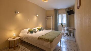 A bedroom with a bed, bedside lamp, and a desk with a chair.