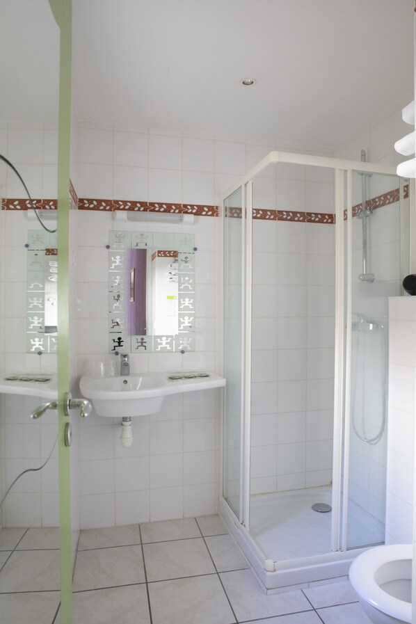 Une salle de bain avec une douche, deux lavabos et des toilettes.