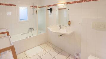 Un baño con bañera, lavamanos, espejo y ducha.