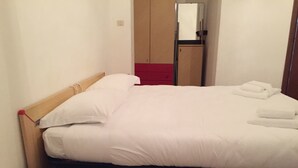 Un lit bien fait, avec du linge de lit blanc et deux serviettes pliées posées sur le côté.