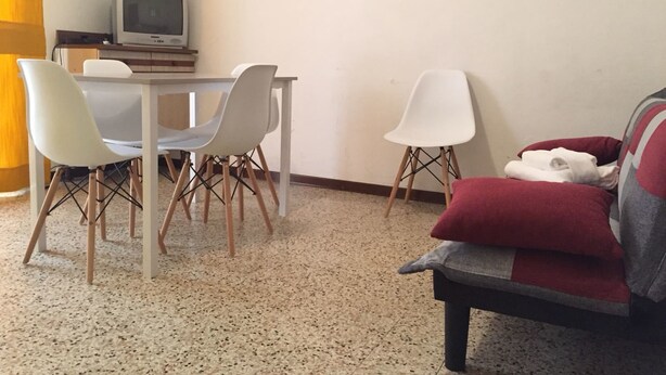 Un salon comprenant une table à manger, deux chaises, un canapé et un téléviseur.