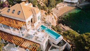 Um imóvel à beira-mar com piscina, área de estar externa e vista para o mar.