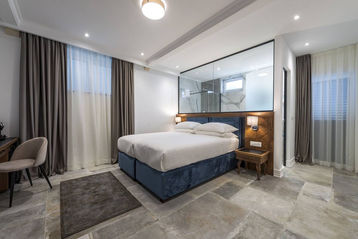 A modern hotel room with a large bed, a desk, and a mirror.