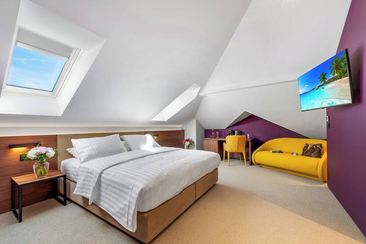 A modern bedroom with a bed, bedside table, and a small desk with a chair.