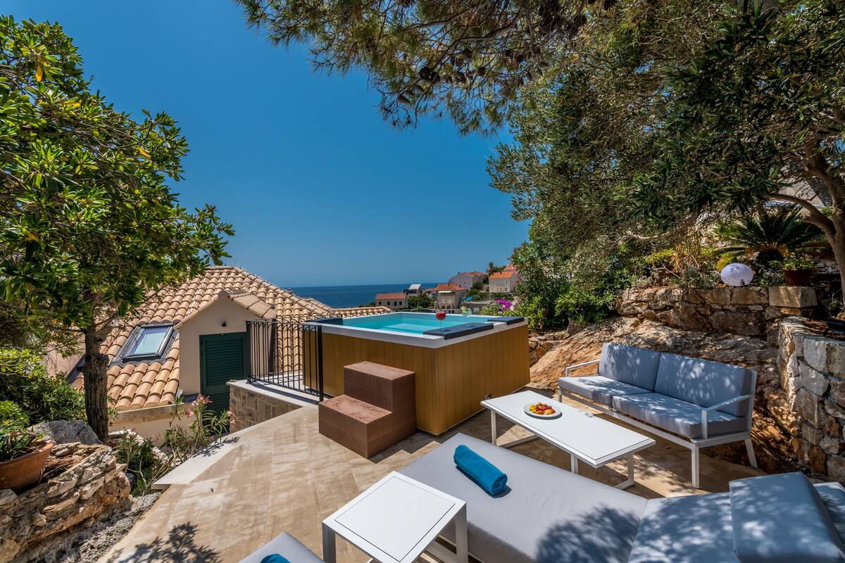 A rooftop terrace with a swimming pool, outdoor seating, and a view of the sea.