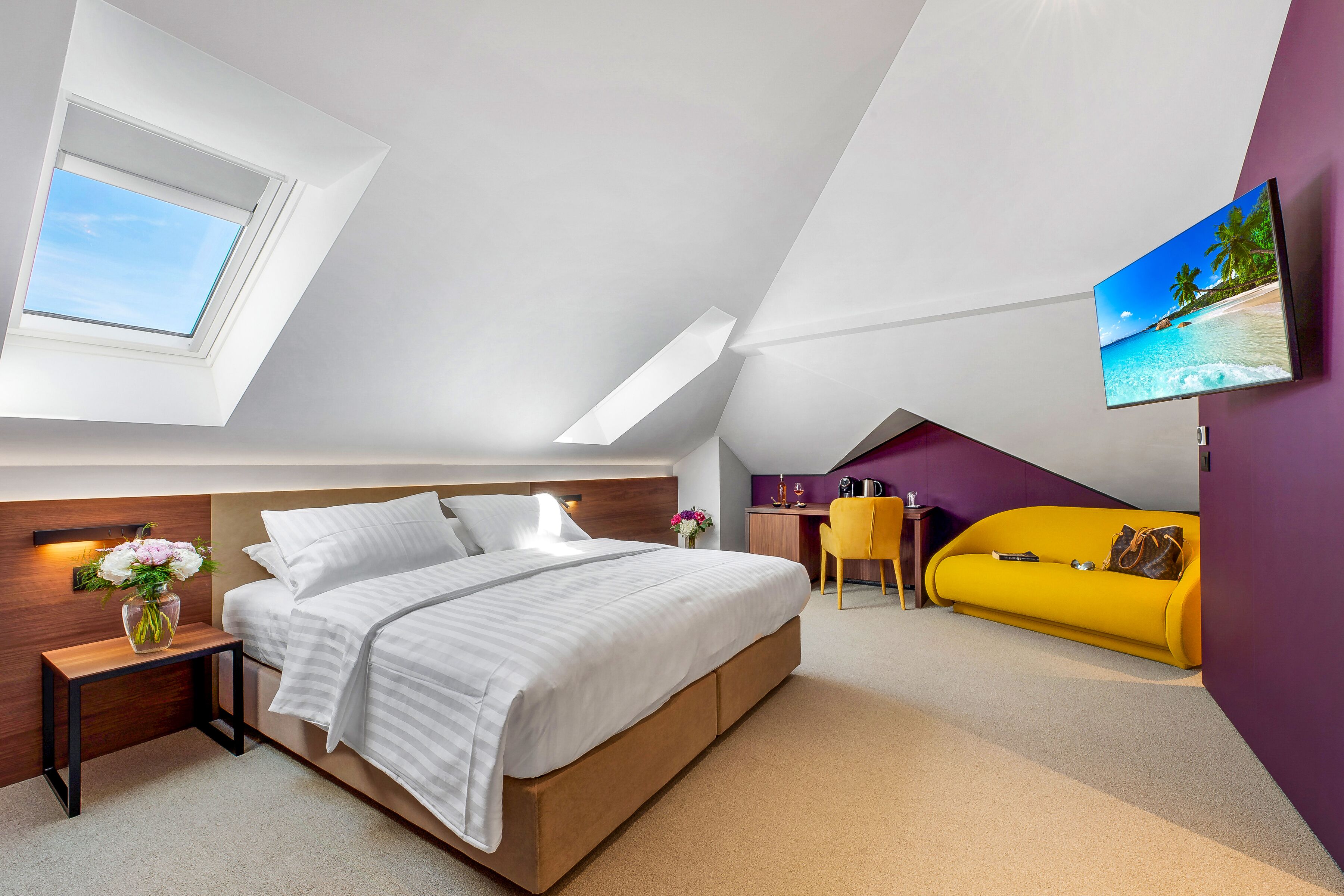 A modern bedroom with a bed, bedside table, and a small desk with a chair.