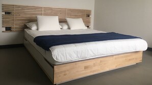 A modern bed with a wooden headboard, white bedding, and a dark blue throw blanket. - Libeccio (Jesolo)