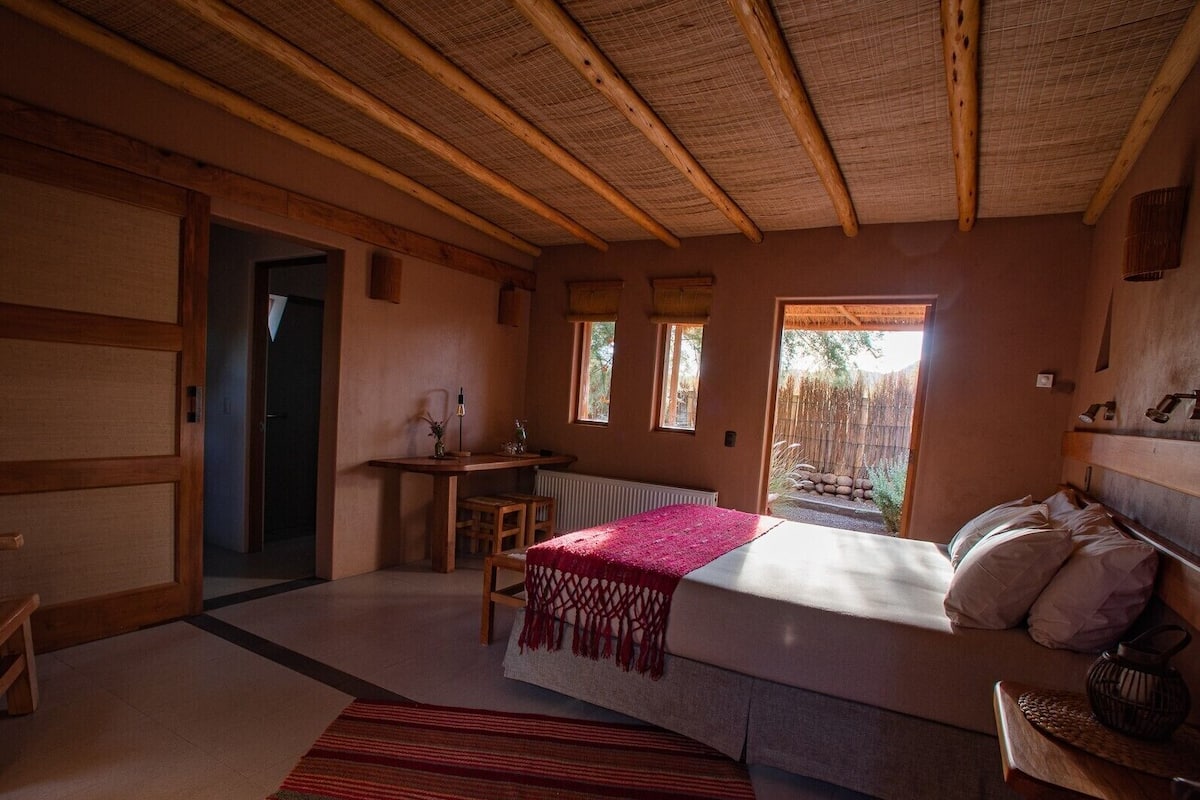 A cozy bedroom with a bed, a desk, and a window.