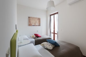 A bedroom with two beds, a window, and a painting on the wall. - Ellebì B&B (Mosciano Sant'Angelo)