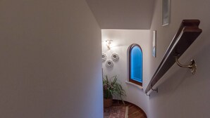 A wooden staircase with a handrail, leading to a landing with a small window and decorative wall sconces. - Ellebì B&B (Mosciano Sant'Angelo)